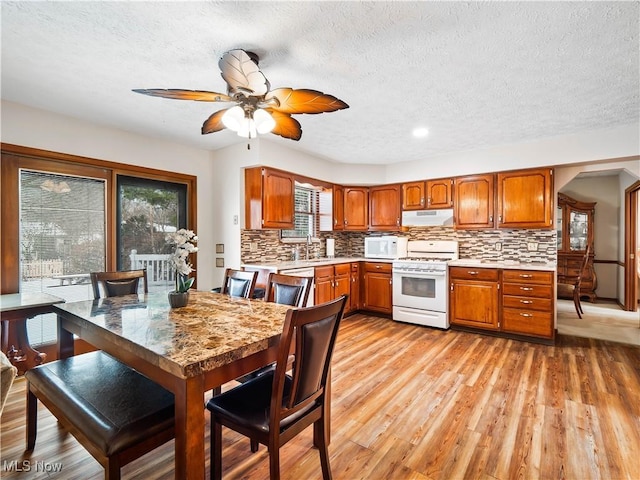 kitchen with sink, white appliances, light hardwood / wood-style flooring, ceiling fan, and backsplash