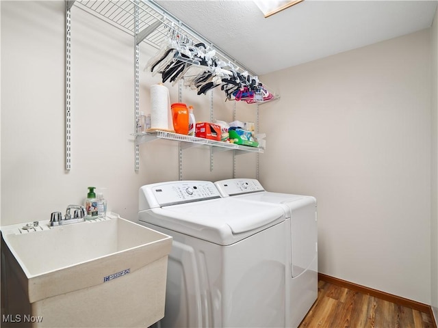 laundry room featuring washing machine and dryer, sink, and hardwood / wood-style floors