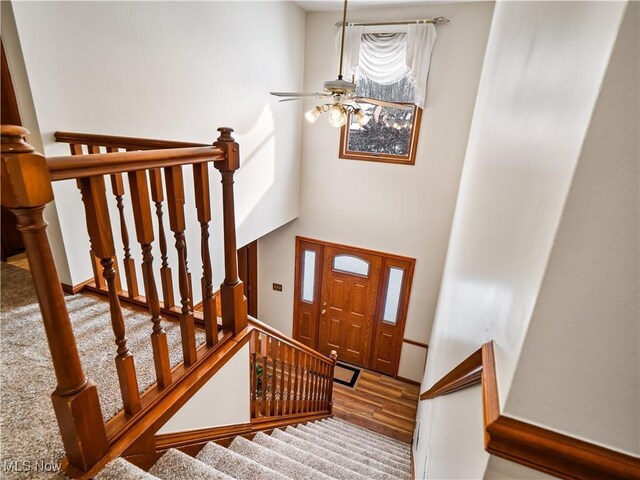 stairs with hardwood / wood-style flooring and ceiling fan