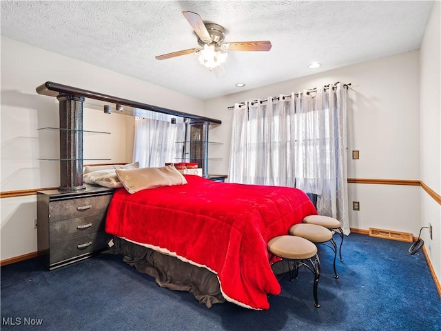 bedroom with ceiling fan, carpet floors, and a textured ceiling