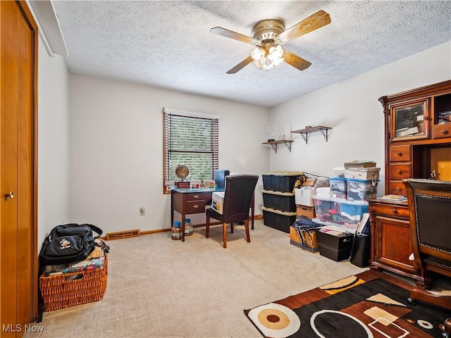 carpeted home office with a textured ceiling and ceiling fan