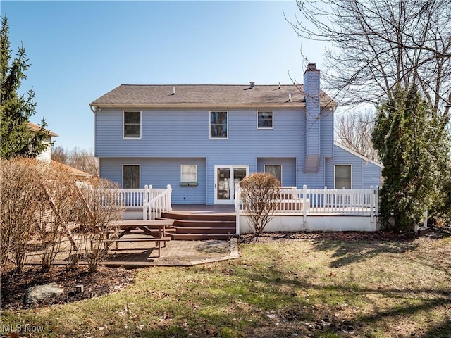 back of property featuring a wooden deck, a lawn, and a chimney