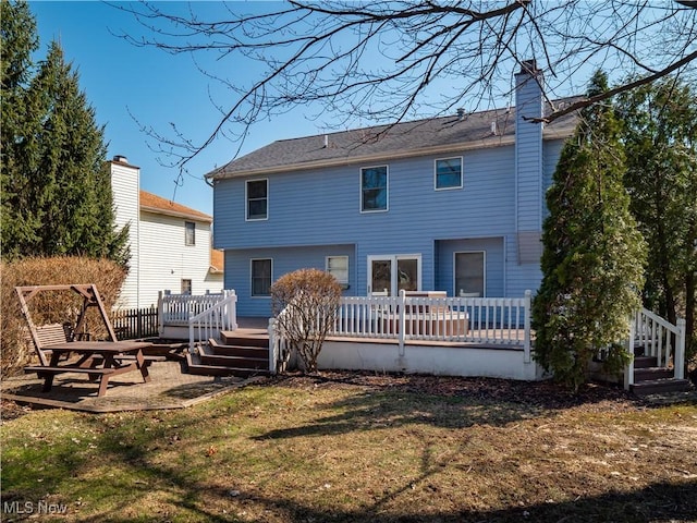 rear view of house featuring a deck, a lawn, and a chimney