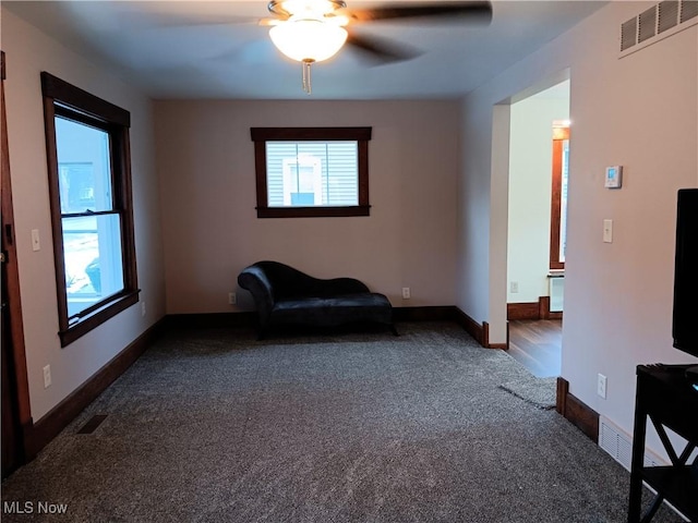 unfurnished room with ceiling fan and dark colored carpet