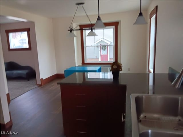 kitchen with sink, decorative light fixtures, and dark wood-type flooring