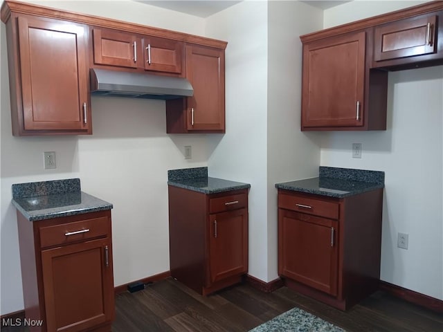 kitchen featuring dark wood-type flooring and dark stone counters