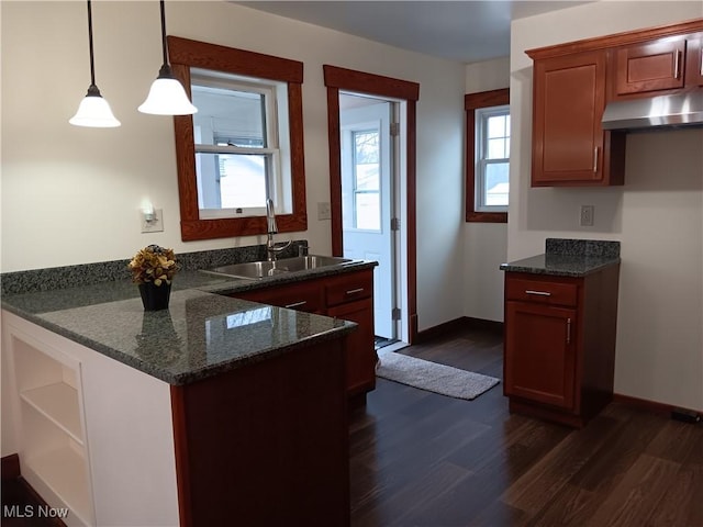 kitchen featuring pendant lighting, dark stone counters, dark hardwood / wood-style floors, and sink