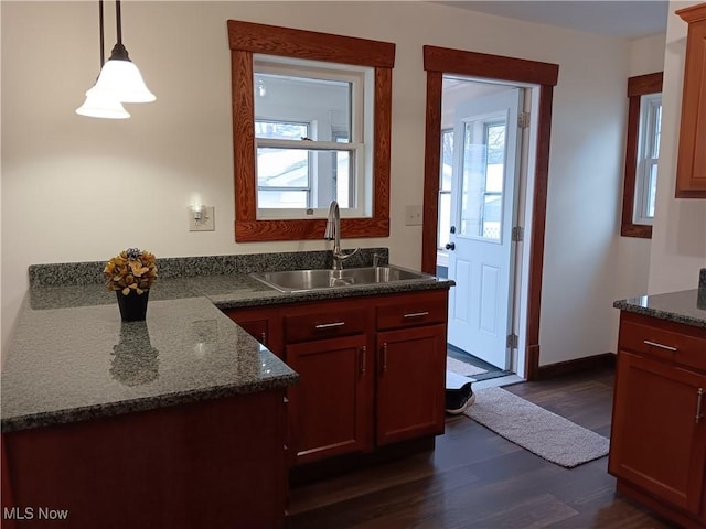 kitchen featuring sink, dark stone countertops, dark hardwood / wood-style floors, and decorative light fixtures