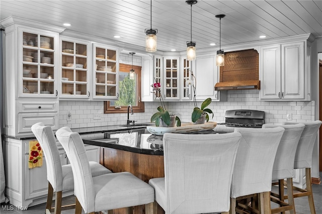 kitchen featuring a kitchen bar, stainless steel gas stove, a sink, tasteful backsplash, and hanging light fixtures