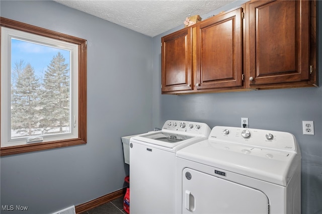 laundry area with baseboards, cabinet space, a textured ceiling, and washing machine and dryer