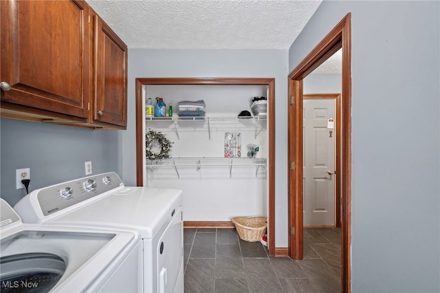 laundry room with washer and dryer, cabinet space, a textured ceiling, and dark tile patterned floors