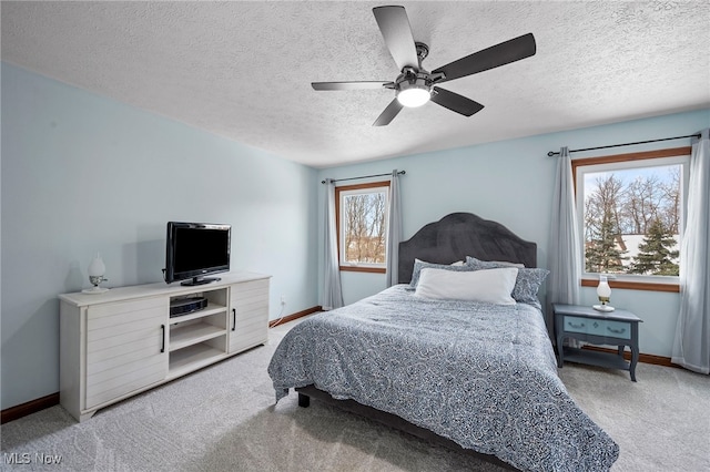 bedroom featuring baseboards, light colored carpet, a ceiling fan, and a textured ceiling