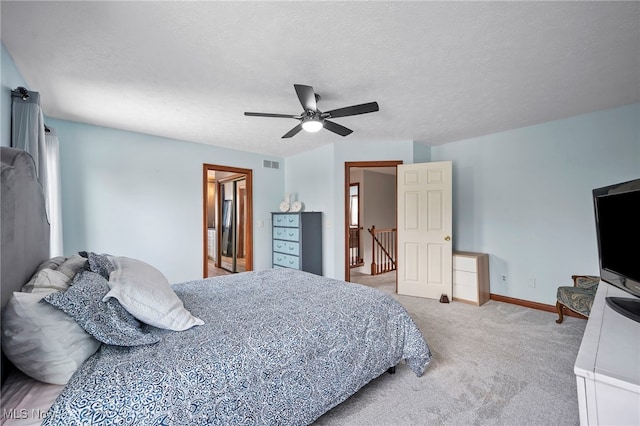 bedroom with visible vents, baseboards, light colored carpet, and a textured ceiling