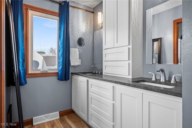 full bathroom with wood finished floors, baseboards, visible vents, and a sink