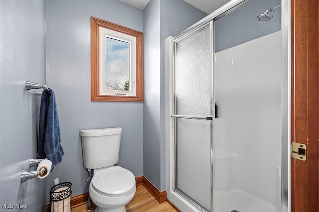 full bath with baseboards, toilet, wood finished floors, and a shower stall