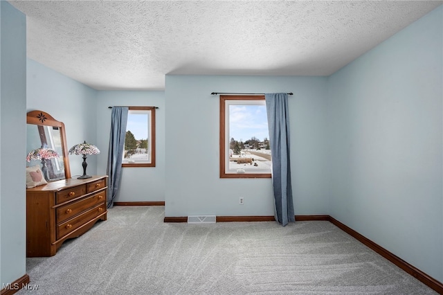 bedroom featuring a textured ceiling, baseboards, visible vents, and light carpet