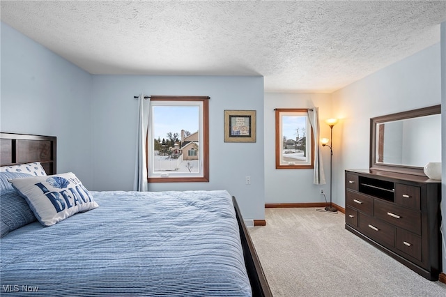 bedroom featuring baseboards, light colored carpet, and a textured ceiling