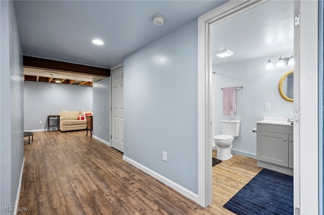 interior space featuring baseboards, toilet, wood finished floors, and vanity