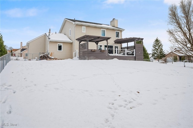 snow covered house with fence, a chimney, and a pergola