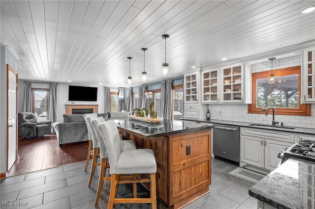 kitchen featuring tasteful backsplash, a breakfast bar, appliances with stainless steel finishes, a fireplace, and a sink