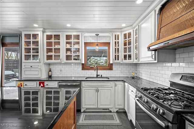 kitchen with glass insert cabinets, stainless steel range with gas cooktop, decorative backsplash, white cabinetry, and a sink