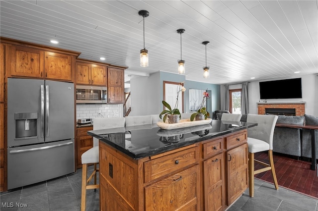 kitchen featuring decorative light fixtures, a breakfast bar, decorative backsplash, brown cabinets, and appliances with stainless steel finishes