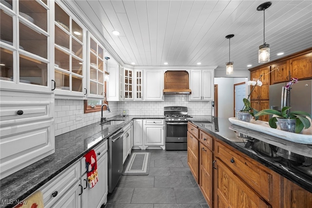 kitchen with tasteful backsplash, custom range hood, white cabinets, stainless steel appliances, and a sink