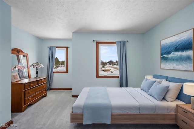 bedroom with a textured ceiling, baseboards, and light carpet