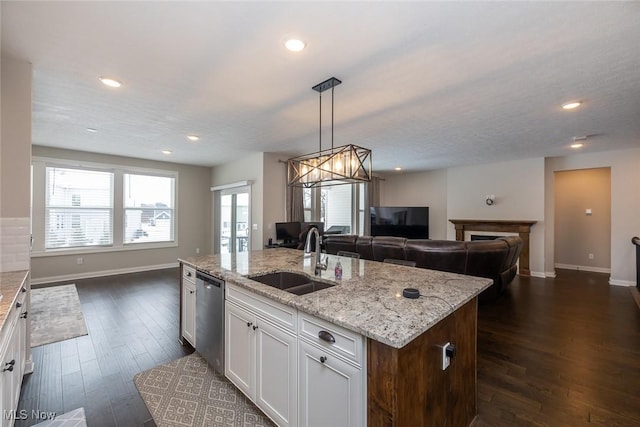 kitchen with pendant lighting, sink, dishwasher, an island with sink, and white cabinets