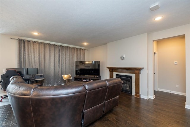 living room with dark hardwood / wood-style flooring and a tiled fireplace