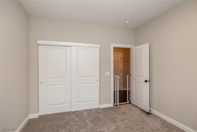 unfurnished bedroom with light colored carpet and a closet