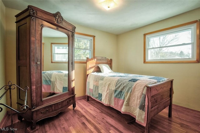 bedroom featuring multiple windows and dark wood-type flooring