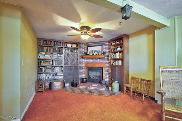 living area featuring built in shelves, carpet flooring, a fireplace, and ceiling fan