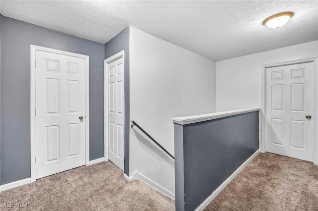 hallway featuring carpet and a textured ceiling