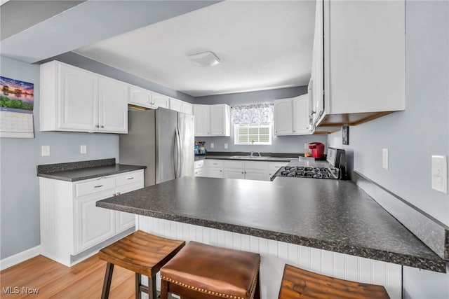 kitchen with stove, a breakfast bar, white cabinets, and kitchen peninsula