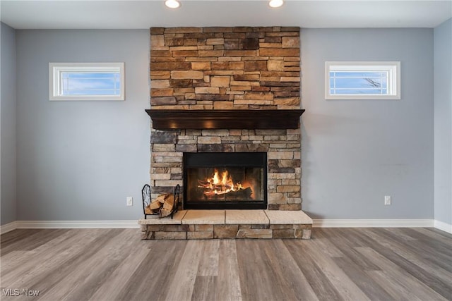 details with hardwood / wood-style floors and a stone fireplace