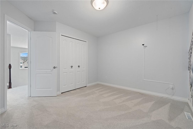 unfurnished bedroom with light carpet and a closet