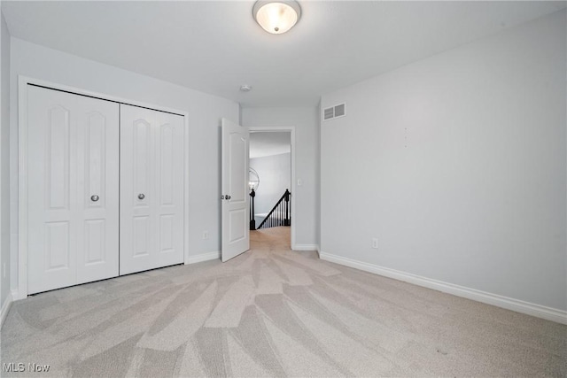 unfurnished bedroom featuring light colored carpet and a closet