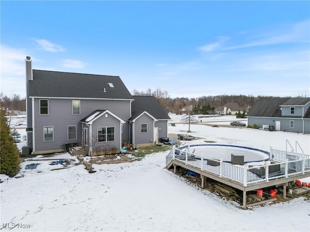 snow covered property featuring cooling unit and a wooden deck