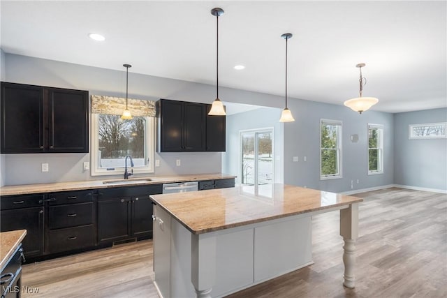 kitchen with decorative light fixtures, a center island, sink, and light stone countertops