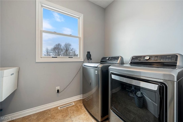 clothes washing area featuring light tile patterned floors and washing machine and dryer