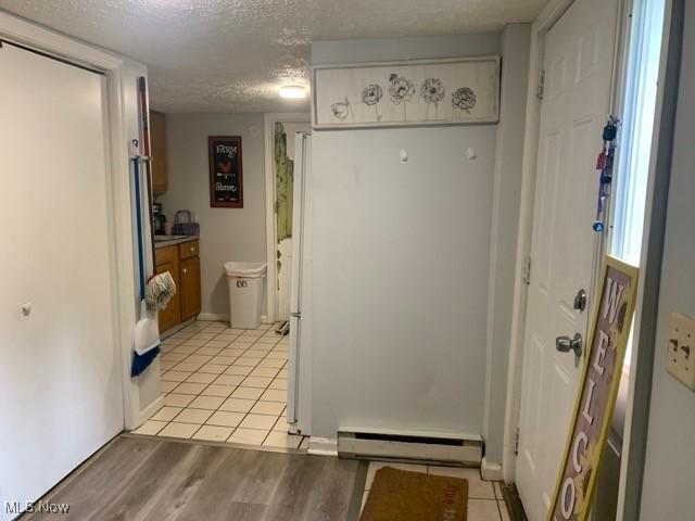 interior space with a baseboard radiator, a textured ceiling, and light wood-type flooring