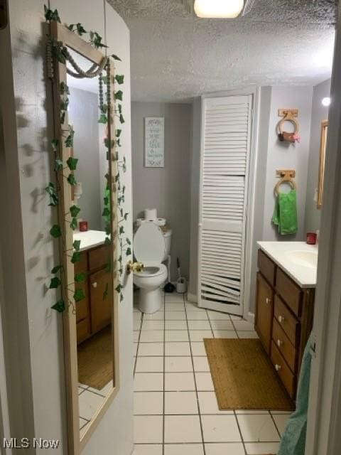 bathroom with tile patterned floors, toilet, a textured ceiling, and vanity