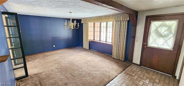 carpeted foyer featuring a chandelier and a textured ceiling