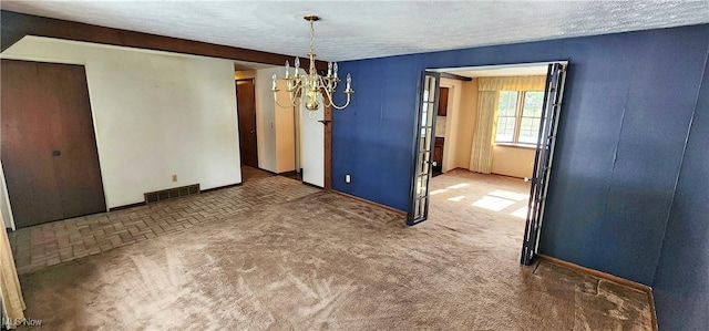 unfurnished dining area with a notable chandelier, a textured ceiling, and carpet flooring