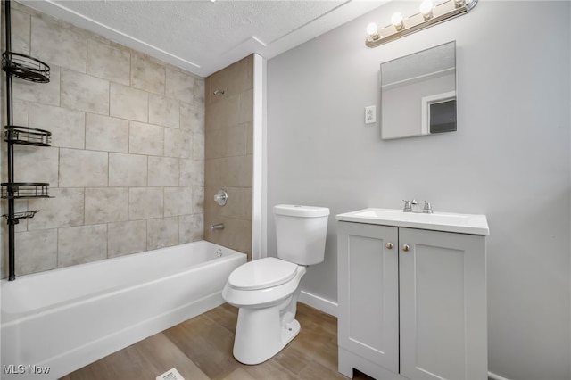 full bathroom with hardwood / wood-style floors, vanity, a textured ceiling, toilet, and tiled shower / bath