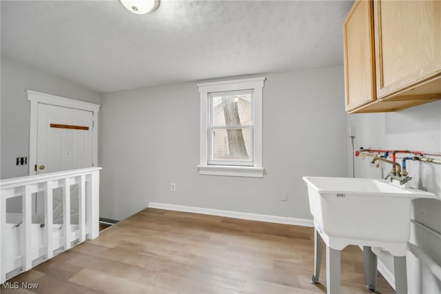 laundry room with cabinets, a textured ceiling, and light hardwood / wood-style floors