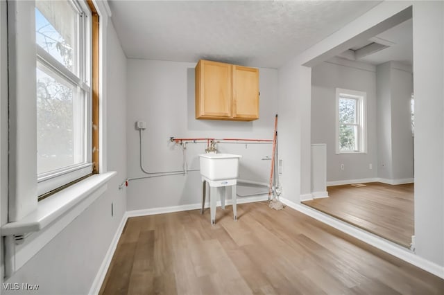 laundry area featuring light hardwood / wood-style floors and a textured ceiling