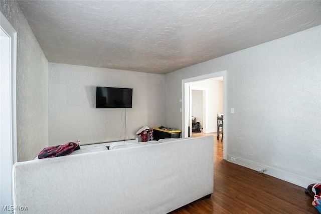 living room featuring a baseboard heating unit, dark wood-type flooring, and a textured ceiling