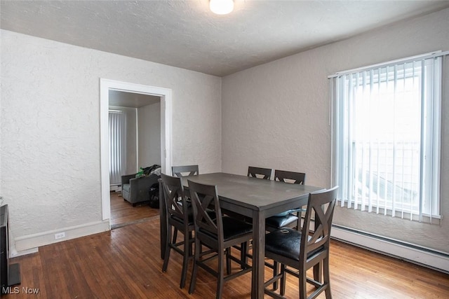 dining area with a baseboard heating unit and hardwood / wood-style flooring